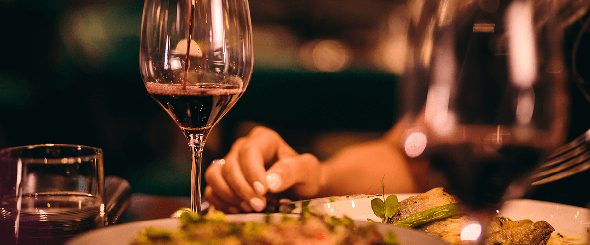 Kulinarisch mit Blick auf den Hafen - Weinglas wird mit Rotwein aufgefüllt | Culinary with a view of the harbour - wine glass is poured with red wine
