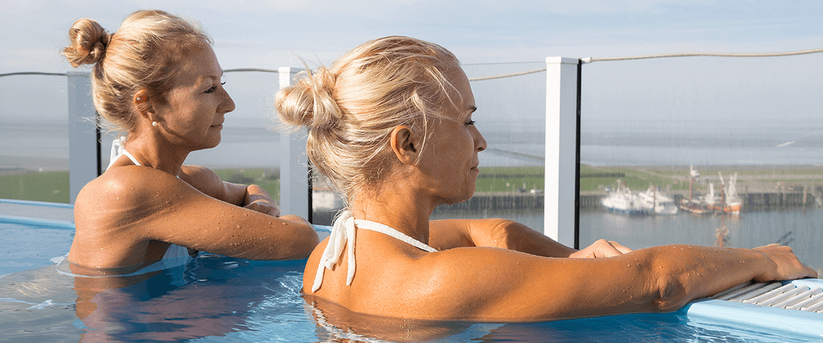 Zwei Frauen genießen den Ausblick vom Infinitypool auf dem Wellnessdeck