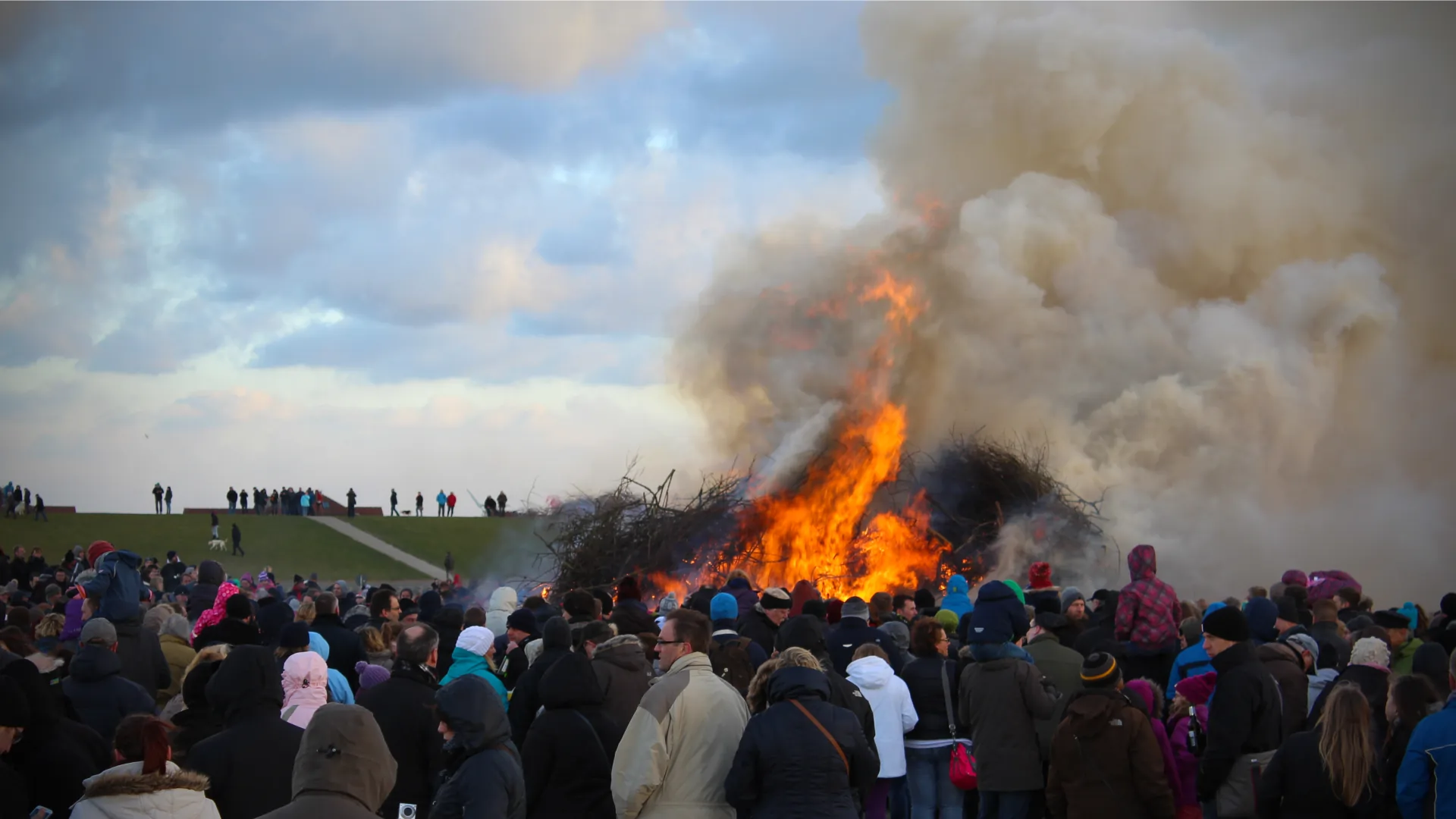 Ostfriesisch Ostern feiern - Gruppe von Menschen beim Osterfeuer am Deich